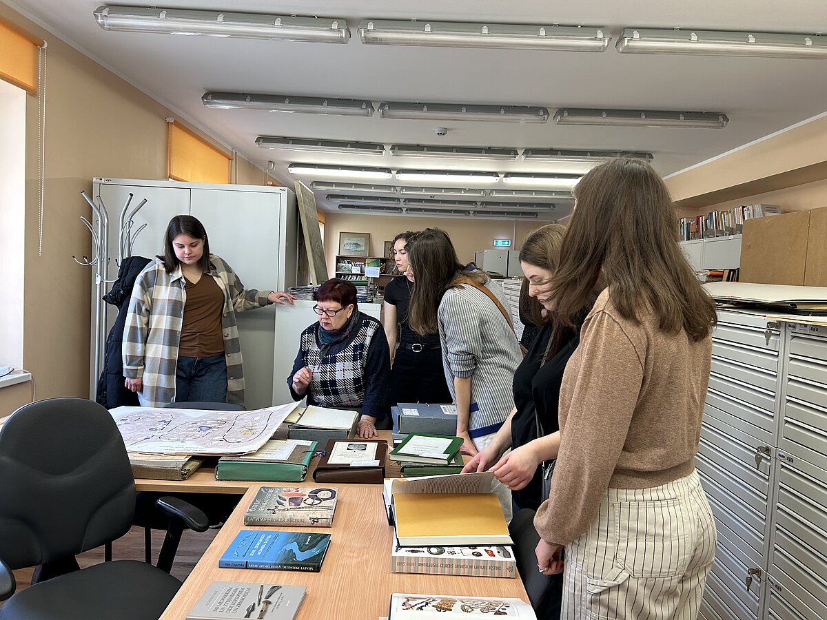 AMK vadītāja Silvija Tilko iepazīstina studentus ar izrakumu zīmētajiem plāniem. Agneses Kukelas foto.
